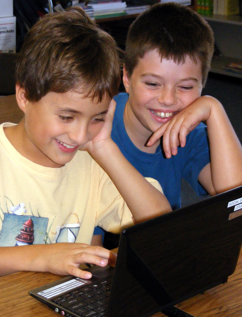 Two boys laughing over computer